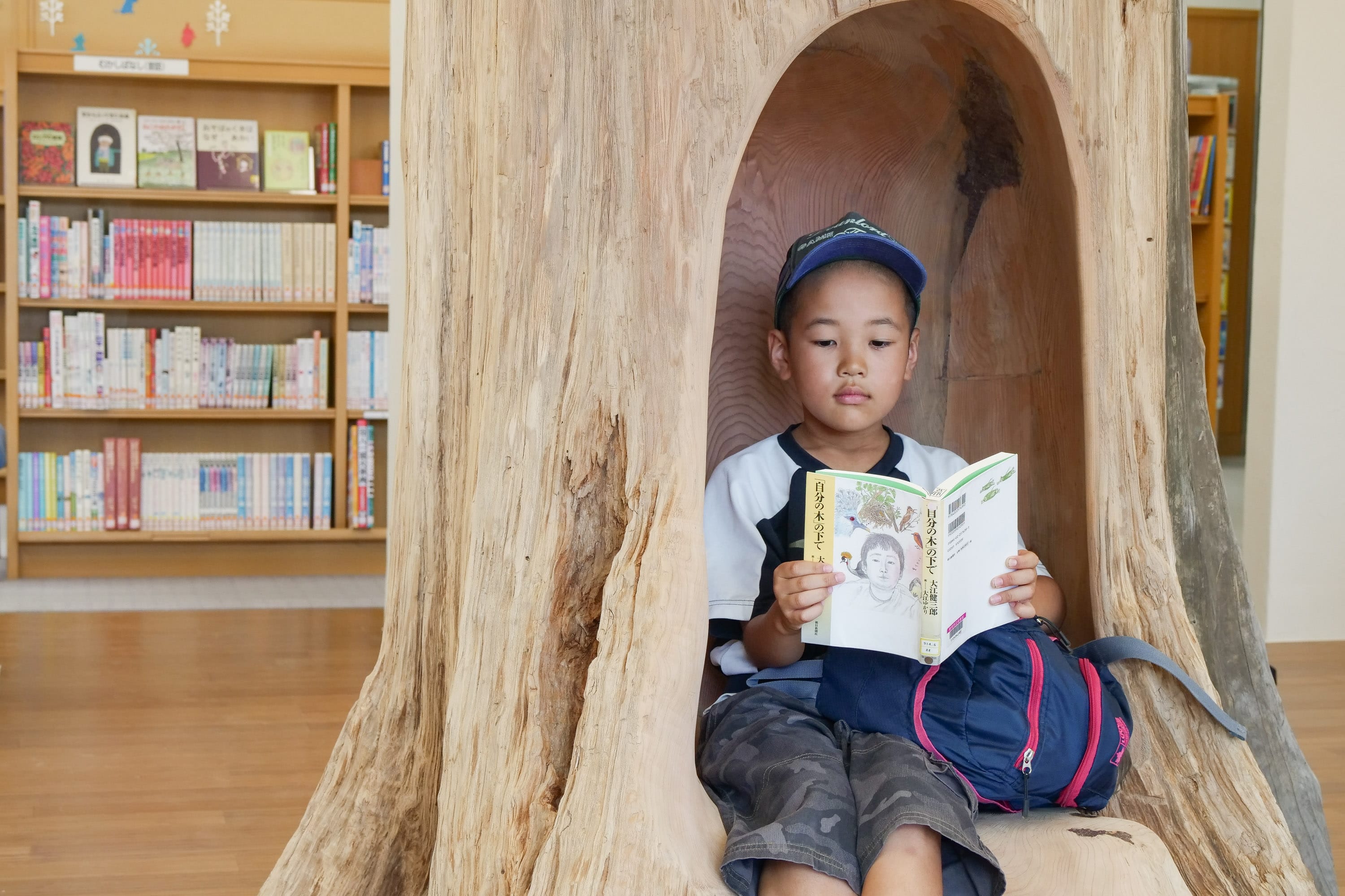 木工作家の吉川和人さんが制作した、樹齢300年の木を使った彫刻作品「自分の木」。ふらっとやってきた近所に暮らす少年が木の中で読んでいたのは、吉川さんが作品の着想を得たという、大江健三郎さんのエッセイ「自分の木の下で」。